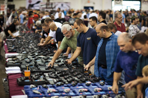 epa03323086 Shoppers examine handguns on display for sale at The Nation's Gun Show held in the Dulles Expo Center in Chantilly, Virginia, USA, 28 July 2012. Gun sales have risen in the U.S. in the wake of the movie theatre shooting massacre in Aurora, Colorado on 20 July. EPA/JIM LO SCALZO